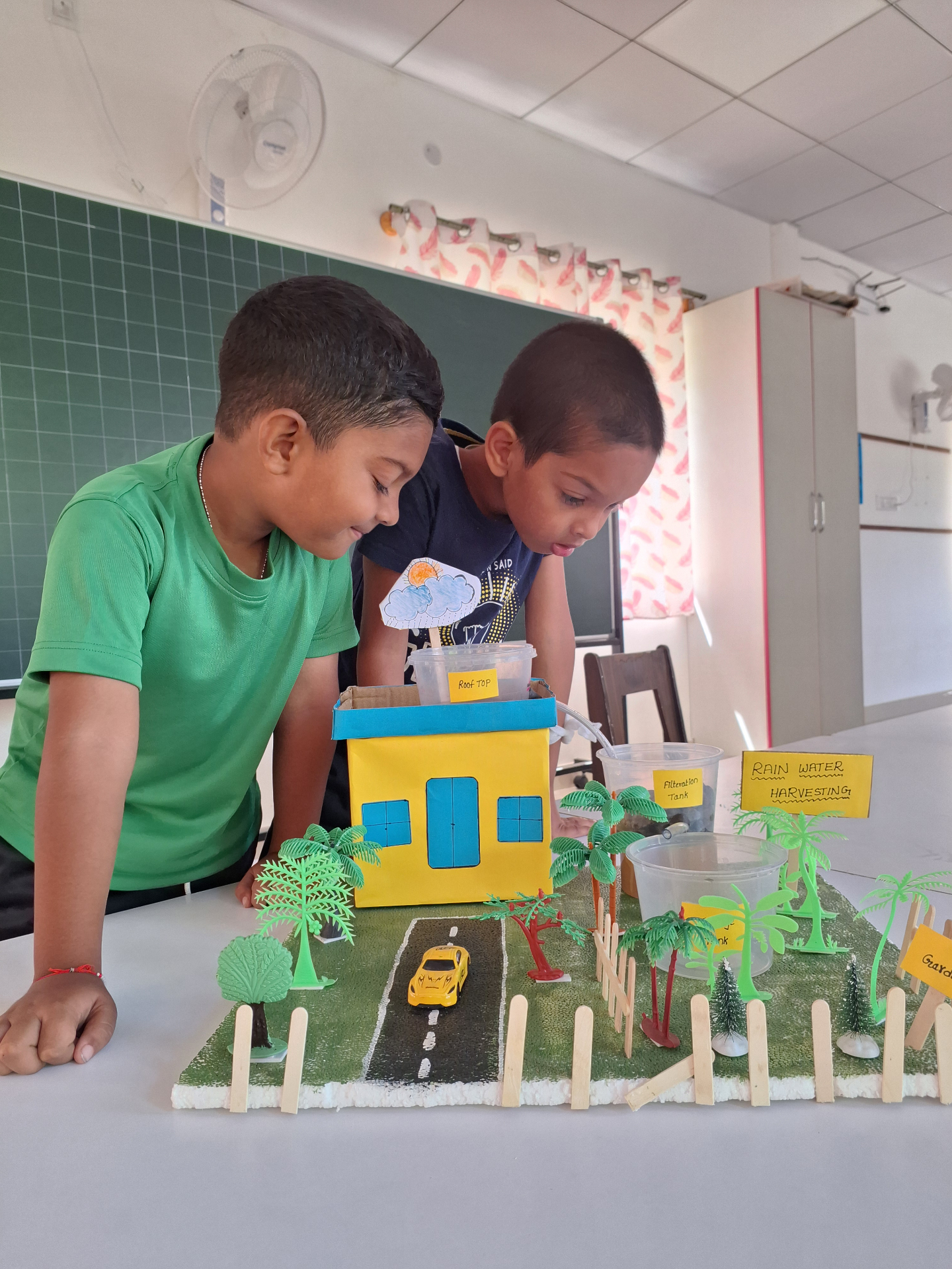 Two children at Arunodeep Montessori exploring a hands-on rainwater-harvesting project in the classroom